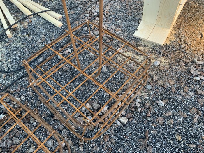 Armeringsjärn för fundament gjutning till carport, med träbitar och grusig mark.