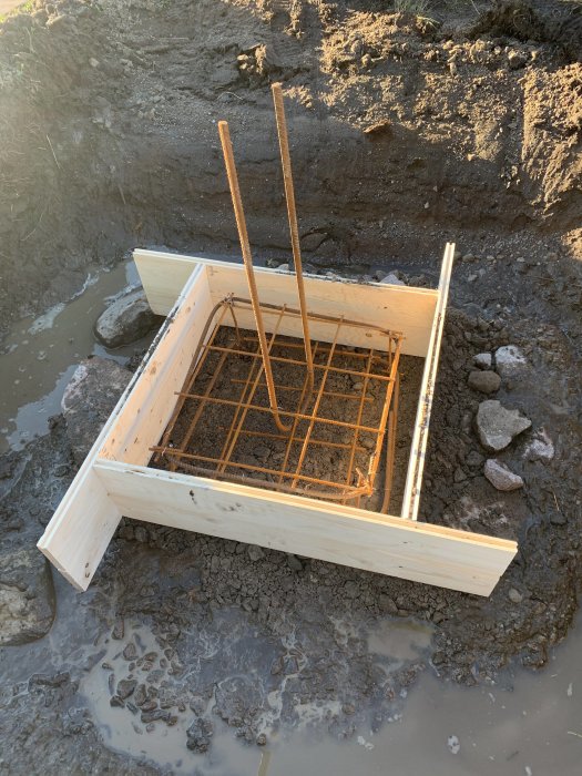 Fundament för carport under gjutning med armeringsjärn och gjutrör i lerig mark.