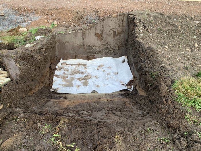 Gjutningsarbete för fundament till carport med synlig armering och duk i utgrävd grop.