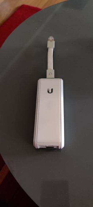 En begagnad Cloudkey originalversion med synliga tecken av dubbelhäftande tejp på den vita baksidan, vilande på en mörk yta.