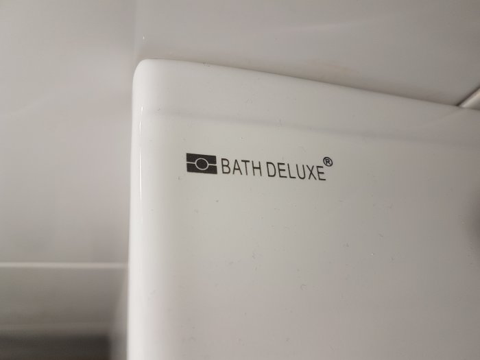 Närbild på en vit yta med logotypen och namnet 'BATH DELUXE' tryckt på den.