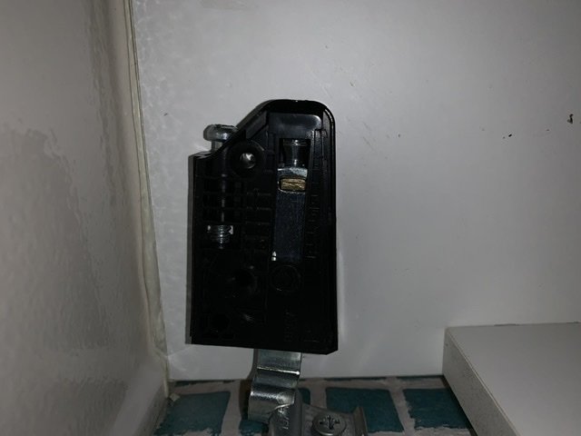 Närbild på ett justerbart fäste för badrumskommod hängandes på en väggskena.