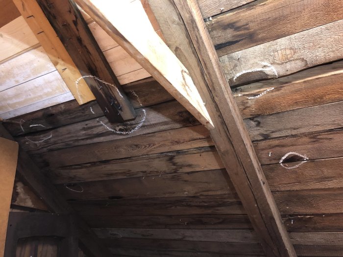Vattenläckage på vind med träbjälkar och mörkt trägolv, synliga vattenfläckar och pölar från regn.