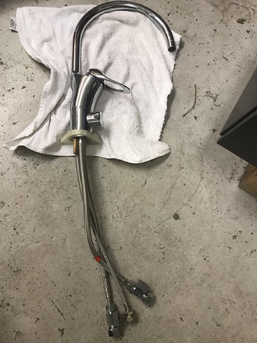 Kromad kran med böjd pip och anslutningsslangar med ballofixventiler på en handduk.