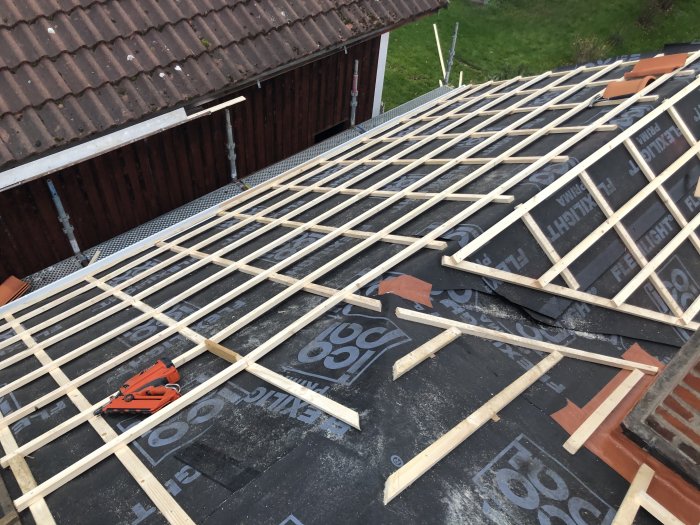 Tak under konstruktion med synliga spikar och klammer som fäster takläkten till underlaget.