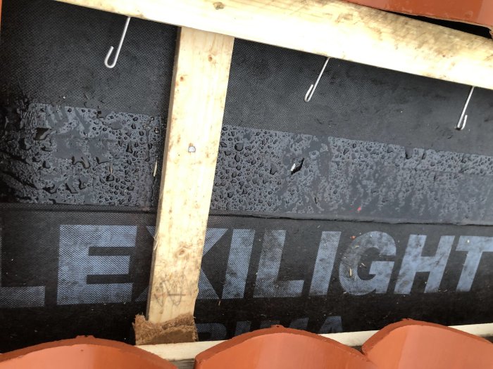 Fuktskyddande papp under takpannor med synliga klammer och spik som diskuterats i inlägget.