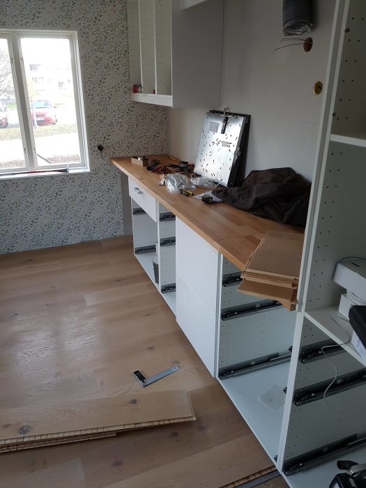 Nyinstallerad ekparkett och vitvaror i ett kök under renovering, med verktyg på bänken.