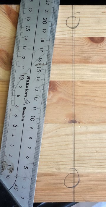 Vinkelhake ligger på träyta med markerad linje som visar räthet.