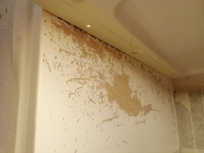 Skadad vitmålad väggstomme med flagnad färg före renovering.