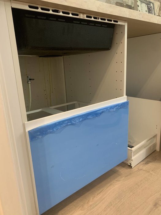 Öppet Ikea köksskåp med Voxtorp lådfront som inte passar på höjden, skenor synliga, skyddsplast kvar.
