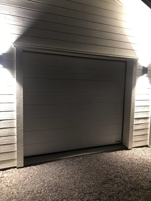 Carport med belyst garageport och väggytor, förberedd för installation av spotar och solceller.