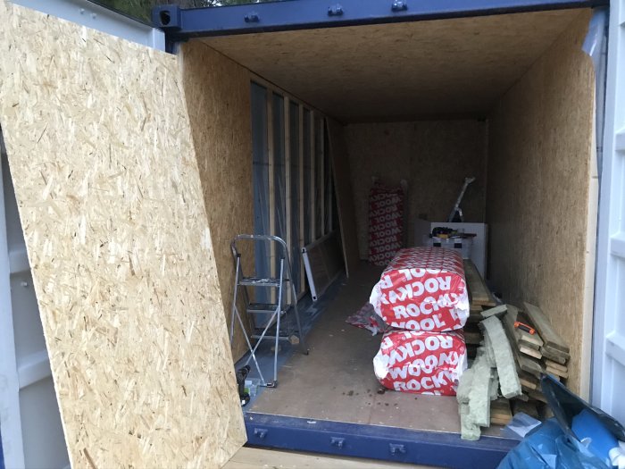 Inre av en 20-fots container isolerad med OSB-paneler, isoleringsmaterial, och byggplast.