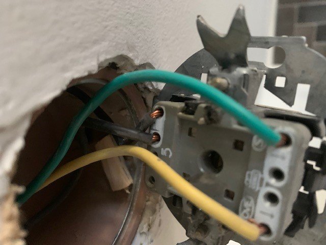 Öppen vägg med synlig strömställare och elektriska kablar i ett byggprojekt.