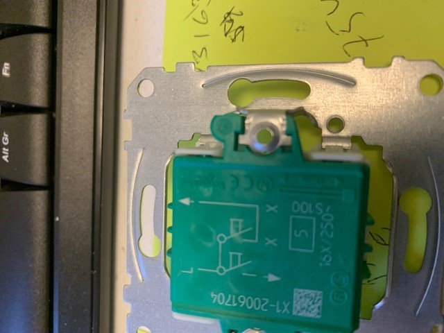 Otydligt foto av en grön 2-krets strömställare nära ett tangentbord och en silverfärgad installationsplåt.