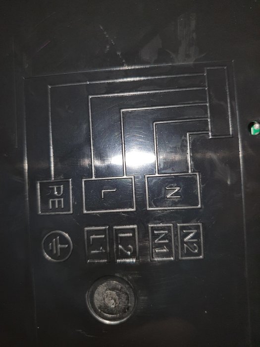 Svart elcentral med kretsschema och säkerhetsbrytare synlig, använd och sliten yta.