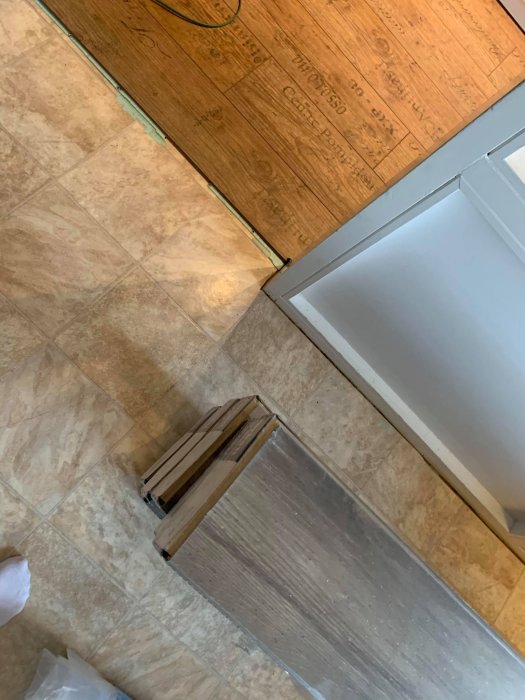 Delvis avlägsnat klickgolv med nakna betongdelar och plastmatta vid diskmaskin.