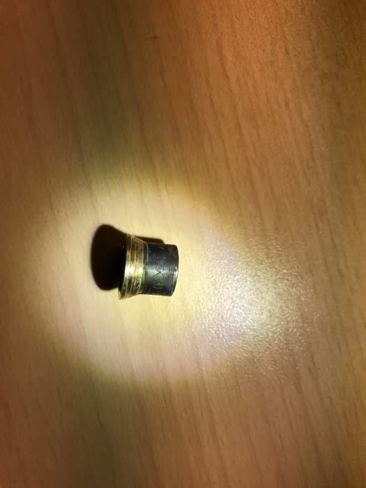 En förminskning med en ända märkt "12x10 mm", möjligen en adapter för rörkoppling, på en enfärgad yta.