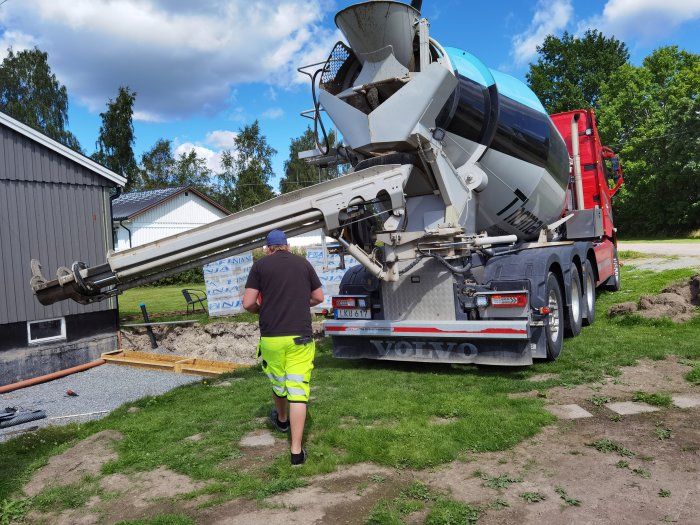 Arbetare övervakar betongleverans från cementblandare till byggarbetsplats.