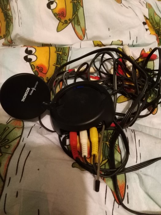 En samling gamla sladdar och kablar inklusive RCA-kablar på ett mönstrat tyg.