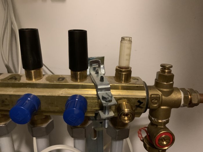 Golvvärmefördelare med svarta och blå ventilkåpor och en flödesmätare som inte rör sig.