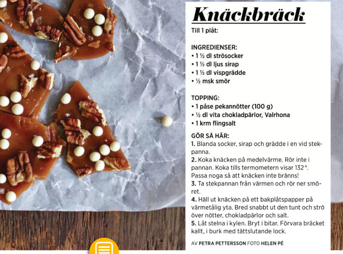 Hembakt knackbräck med pekannötter och vita chokladpärlor på bakplåtspapper.