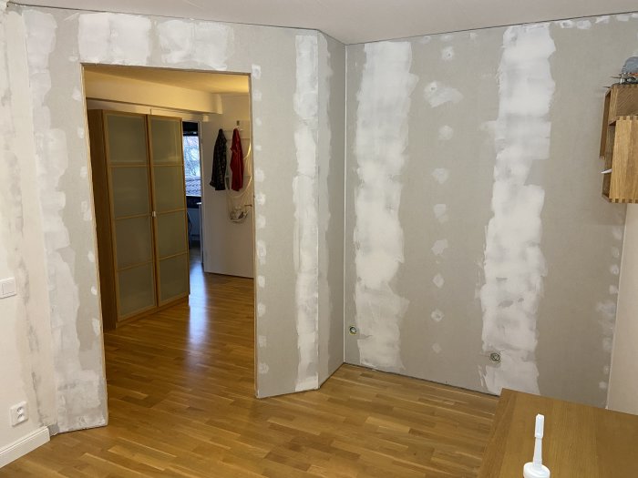 Vägg under renovering med spacklade glipor och höjdskillnader, och synlig målarfog.