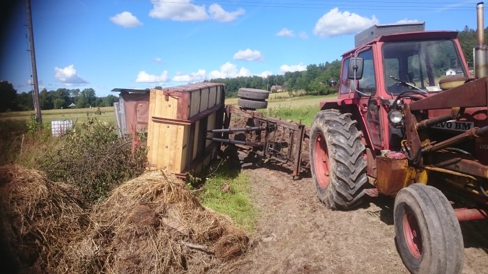 Tippkärran efter reparation med nytt flak bredvid en röd traktor på en byggarbetsplats.