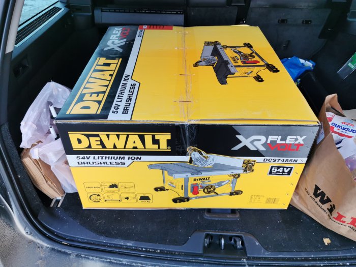 Nyinköpt Dewalt 54V batteridriven bordsåg i oöppnad förpackning i bagageutrymmet på en bil.