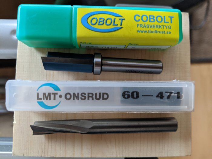 Förpackningar med verktyg för CNC-bearbetning inklusive spiralstål och fräsverktyg på träyta.