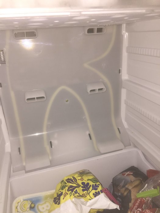 Interiör av en öppen frys med några matförpackningar och tomma lådor, ingen frostsynlig.