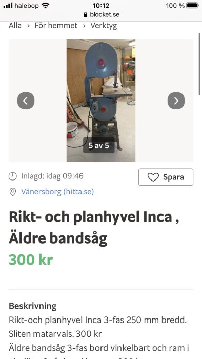 Äldre blå bandsåg av märket Inca med träbit på arbetsbordet, placerad i en verkstad.