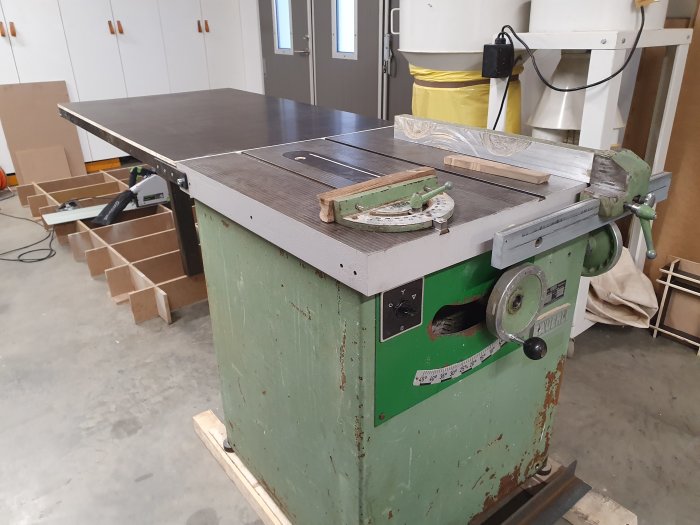 En bordssåg med en nybyggd förlängning på sidan i ett verkstadsutrymme.