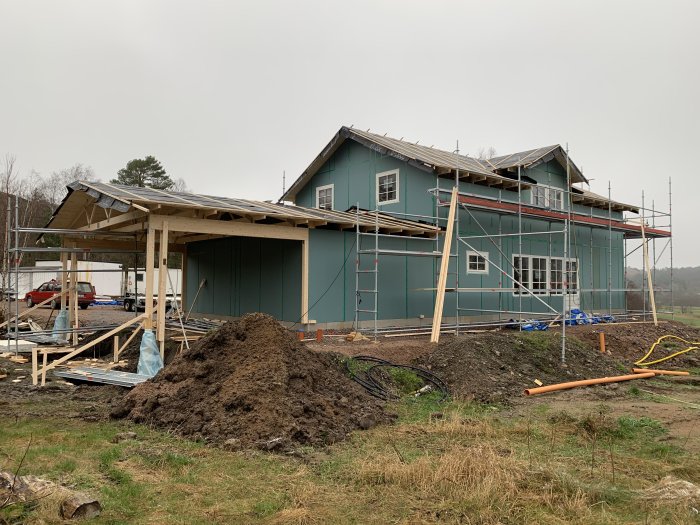 Hus under ombyggnad med ställningar och ett hög av jord i förgrunden.