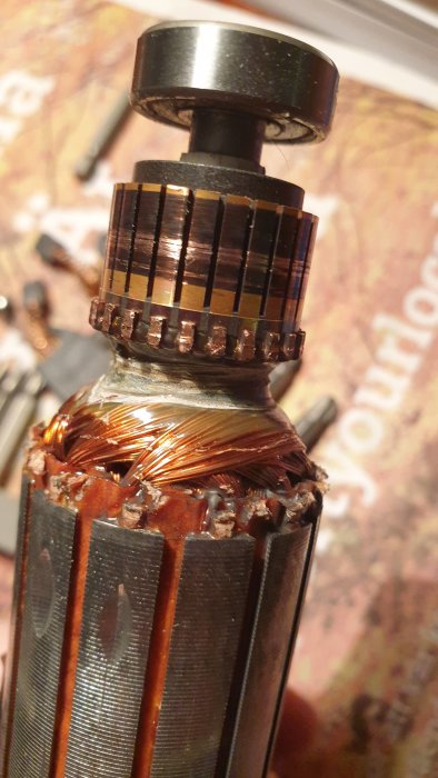 Närbild av en öppnad elektrisk motor till Bosch GKF600 kantfräs med kopparband och spolar.