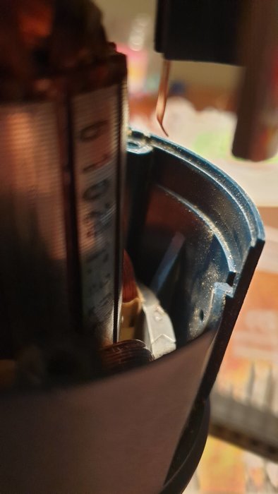 Närbild av en öppnad Bosch GKF600 kantfräs med fokus på inre komponenter och kopparband.