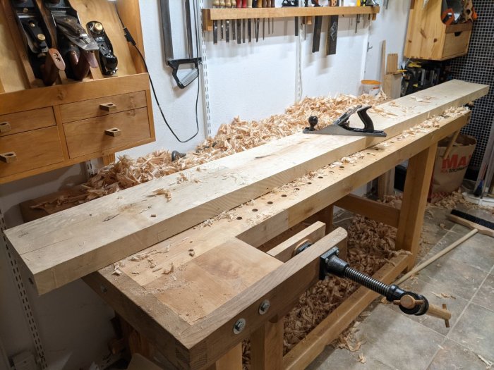 Ett arbetsbänk i ett snickarverkstad med hyvelspån och en handhyvel på ett plank.