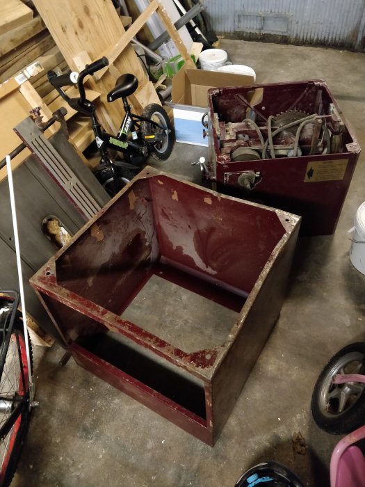 Tomt rödfärgat släpvagnschassi i en rörig garageverkstad, växelspak synlig.