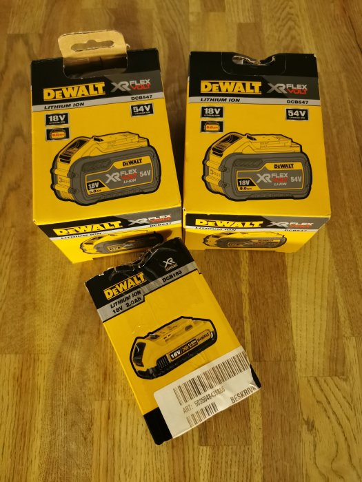 DeWalt batteripaket, två 9ah Flexvolt och ett 2ah 18v, på trägolv.