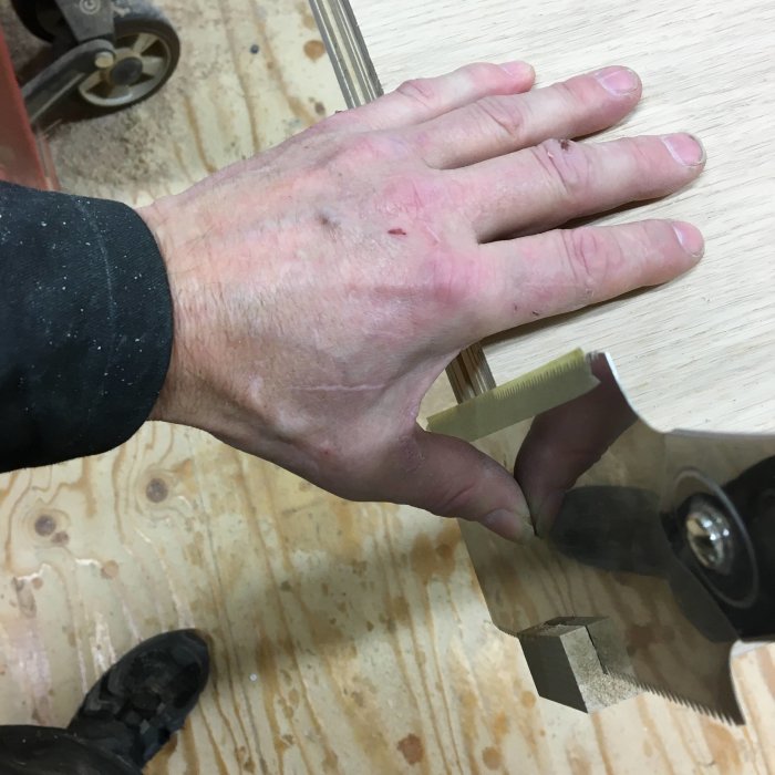 Hand som håller i en japansåg modifierad med maskeringstejp för att skydda fingrarna vid sågning.