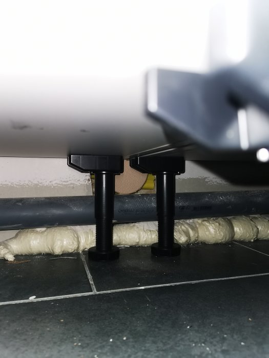 Kabelrör och isoleringsskum under spishäll, synligt gammalt eluttag och ny lucka.