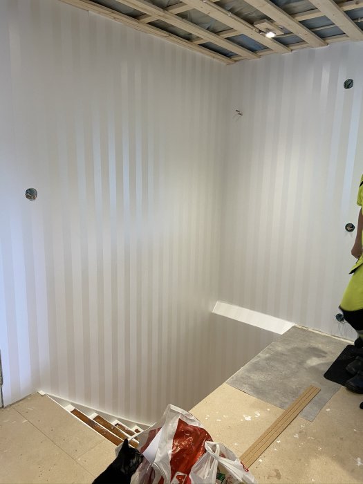 Ett rum under renovering med nyuppsatt randig tapet och öppningar för dörrar.