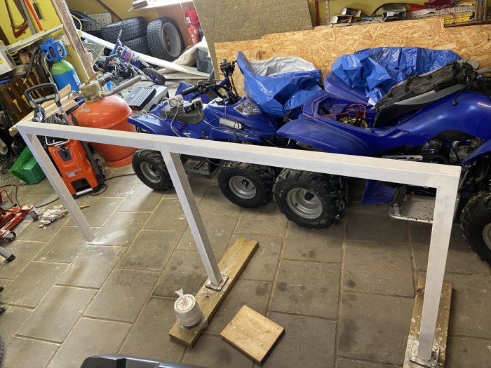 Vit målad trappa eller räcke i en rörig garageverkstad med ATV och verktyg.