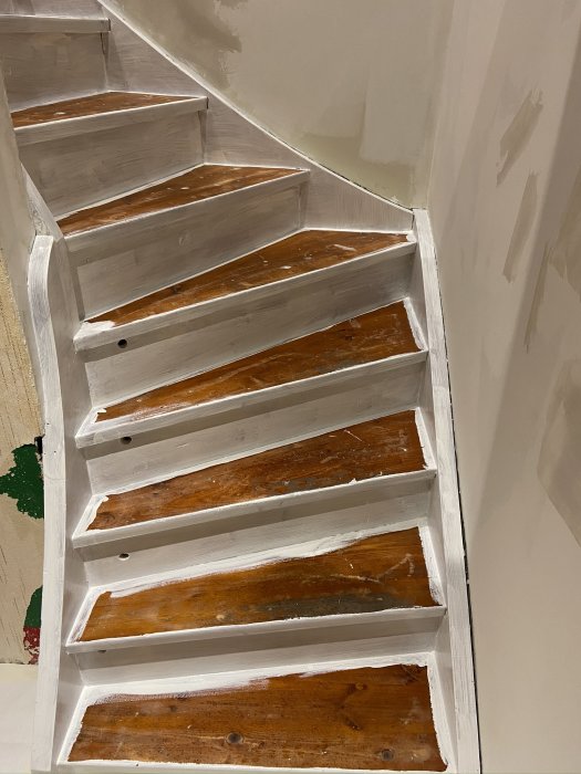 Trappa med vita sidor och brunmålade steg förberedda för golvläggning.