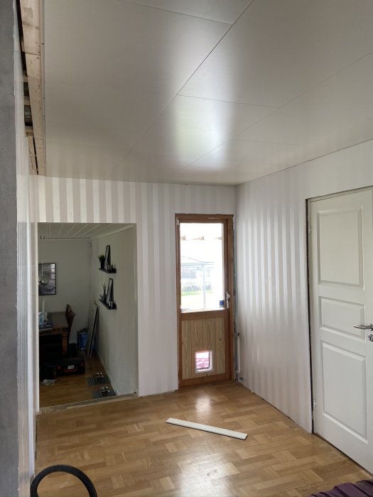 Omonterat innertak med synliga skarvar i rum, parkettgolv och dörr i bakgrunden.