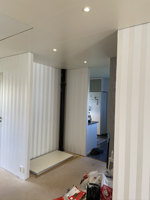 Renoverat rum med halvt installerat innertak och spotlights, byggmaterial på golvet.