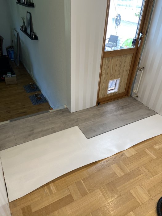 Installation av ett vinylklickgolv bredvid befintligt parkettgolv i en hall.