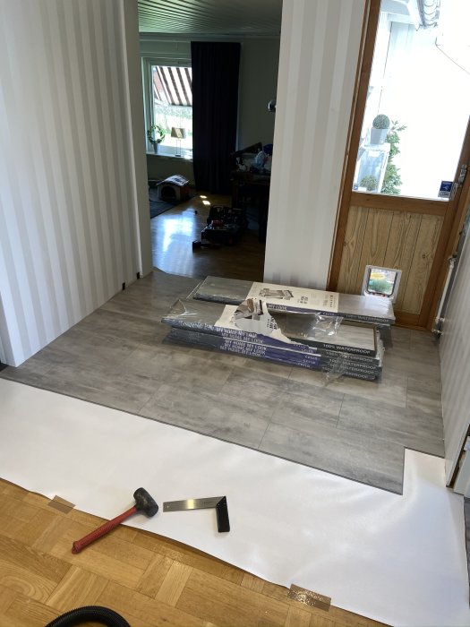 Installation av vattentåligt vinylklickgolv med verktyg och golvpaket synliga.