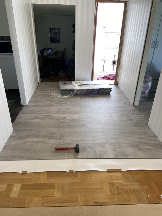 Installation av vattentåligt vinylklickgolv med verktyg synligt på det halvlagda golvet.