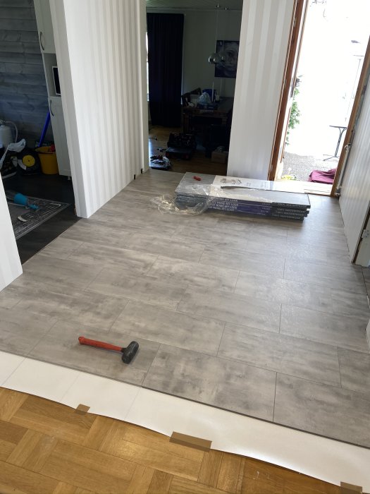Installation av grått vinylklickgolv i ett hem, halvlagt med verktyg på golvet.