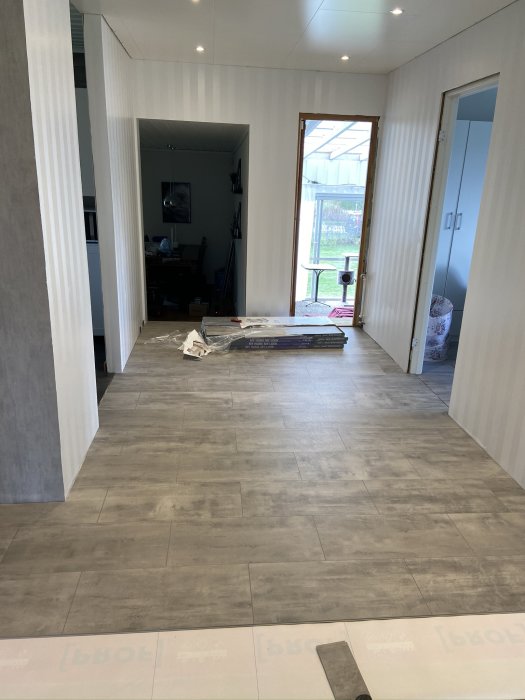 Nyinstallerat vattentåligt vinylklickgolv i en hall med halvlägt golv och verktyg synliga.